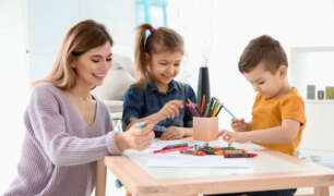 Nanny helping children draw