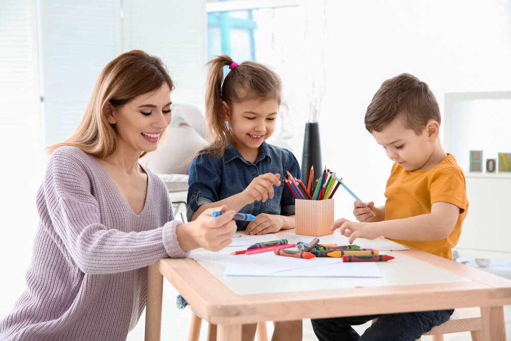 Nanny helping children draw