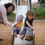 summer nanny with children on park slide