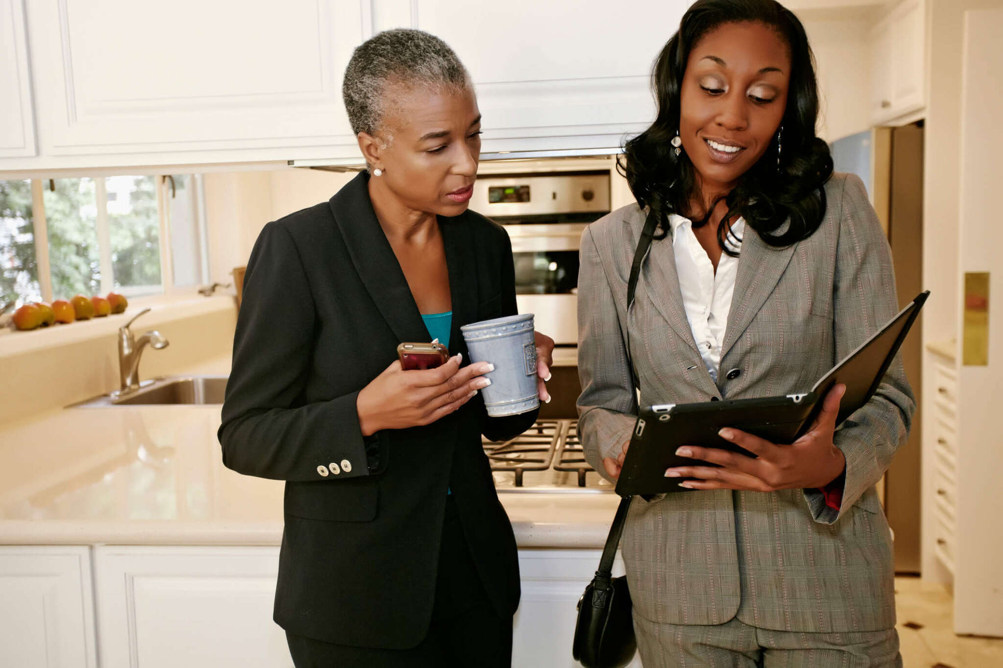 Executive assistant talking in kitchen to her boss