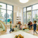 Pre-school teacher and children in playing in learning room in daycare