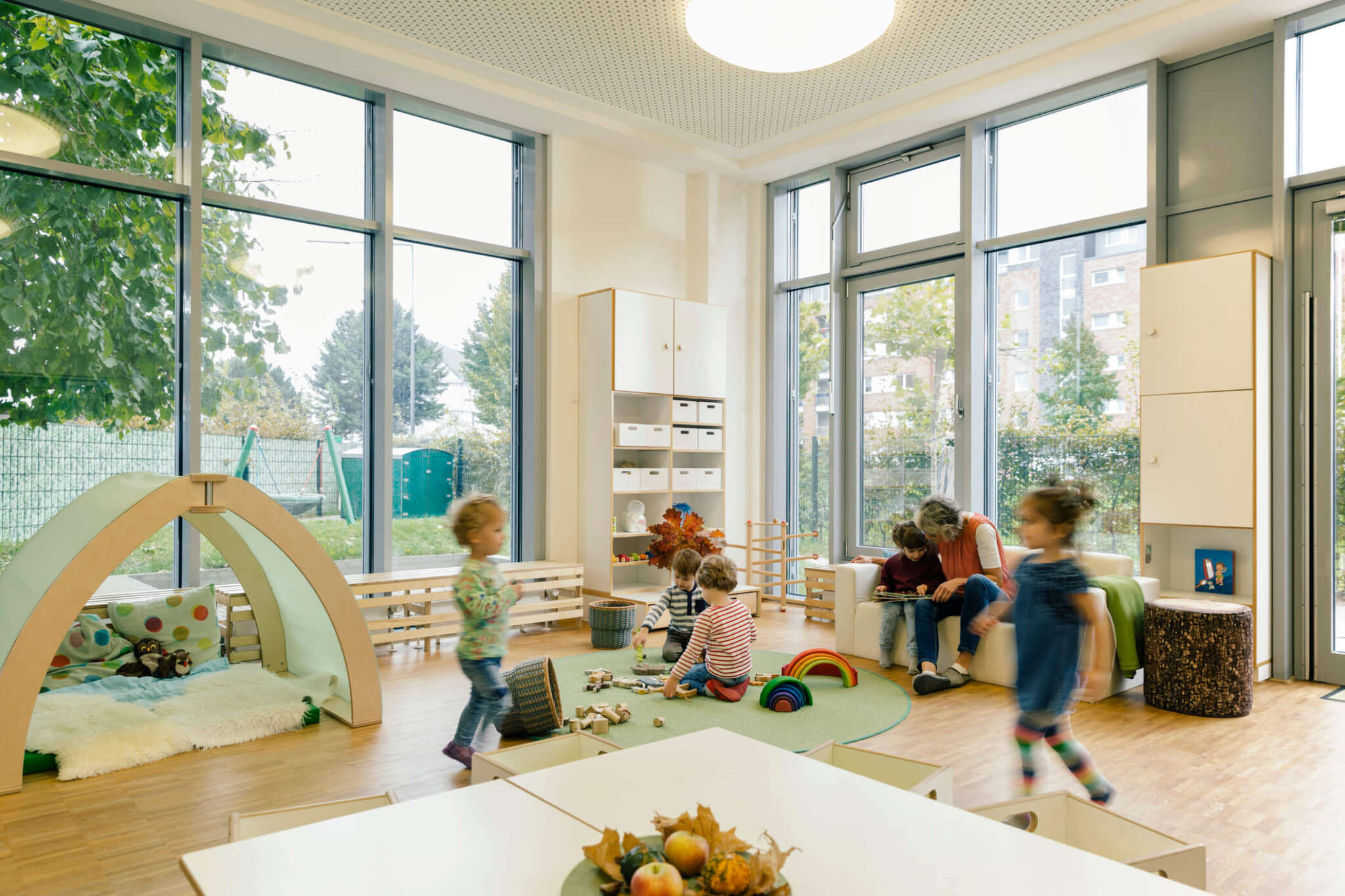 Pre-school teacher and children in playing in learning room in daycare