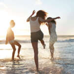 Young women hanging out at the beach, at sunset