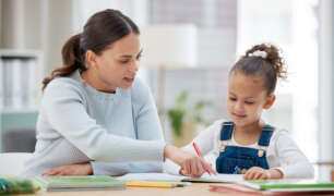 Young girl learning with a nanny homeschool teacher one-on-one at home