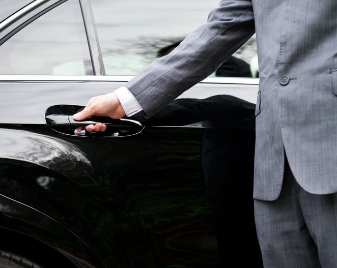 Chauffeur opening a car door as part of a coordinated nanny and chauffeur childcare routine