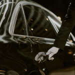 Male Chauffeur Opening Luxury Car Door for Passenger at Night
