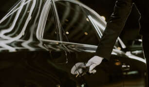 Male Chauffeur Opening Luxury Car Door for Passenger at Night