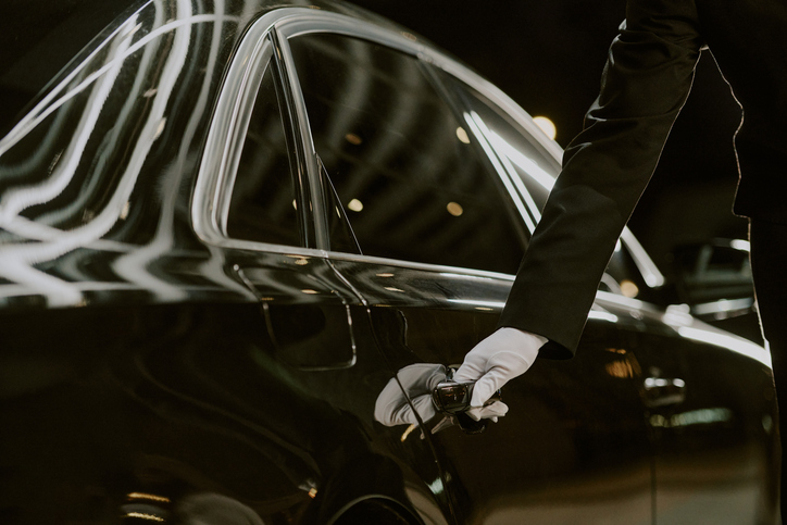 Male Chauffeur Opening Luxury Car Door for Passenger at Night
